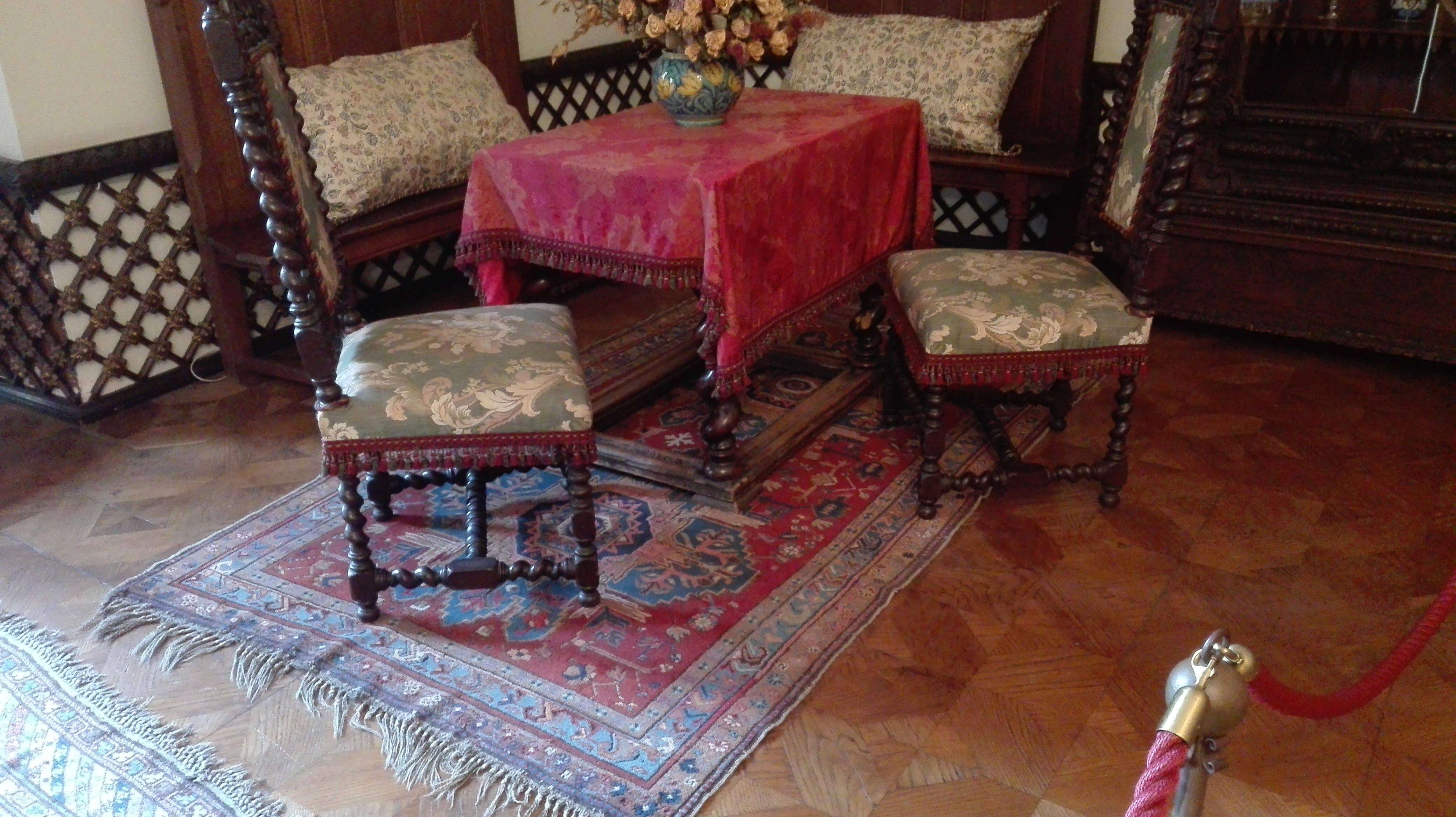 stół i krzesła oraz czerwony ornamentalny dywan w dworku