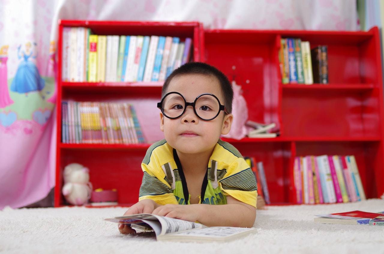 chłopczyk w okrągłych okularach oglądający książkę